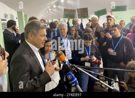 Baku, Aserbaidschan. November 2024. Robert Habeck (Bündnis 90/die Grünen), Bundesminister für Wirtschaft und Klimaschutz und Spitzenkandidat der Grünen für die Bundestagswahl 2025, spricht auf der Weltklimakonferenz. Im Hintergrund stehen Aktivisten mit Plakaten. Habeck ist trotz der Regierungskrise zur Weltklimakonferenz in Aserbaidschan gereist. Quelle: Torsten Holz/dpa/Alamy Live News Stockfoto