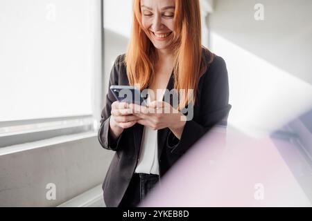 Rothaarige Frau mit Smartphone Stockfoto