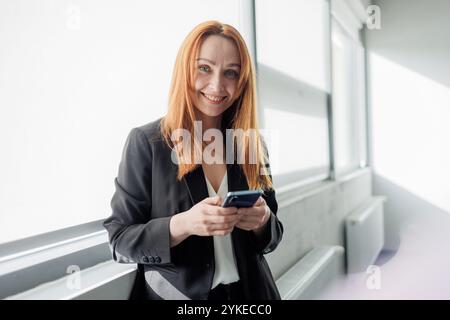 Geschäftsfrau mit Smartphone im modernen Büro Stockfoto