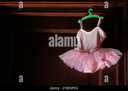 Pinkfarbenes Tutu für Baby oder Puppe, das an einer Holztür hängt Stockfoto