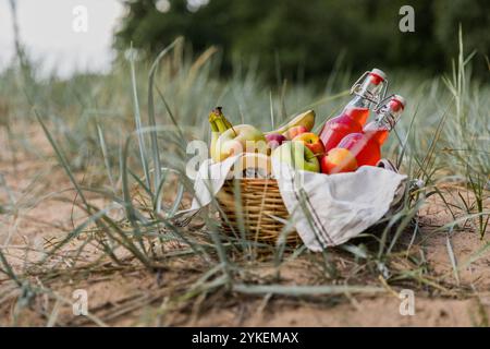 Picknickkorb mit Obst und Saft am Strand Stockfoto