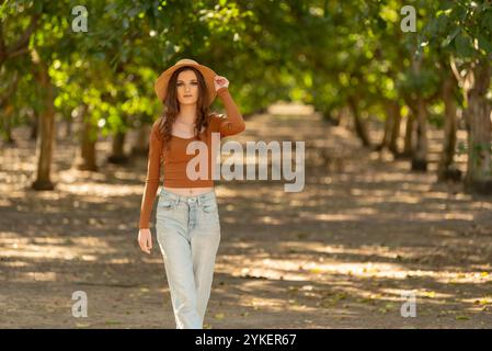 Frau, die einen Hut im Obstgarten auf einer rustikalen Farm trägt Stockfoto