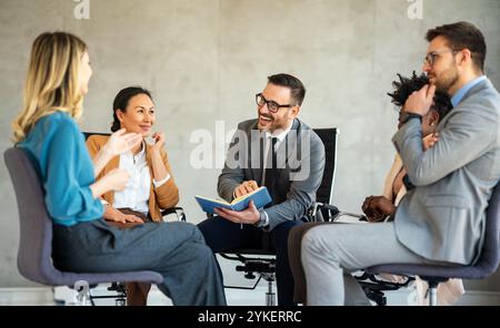 Glückliche Geschäftsleute lachen, während sie an einem neuen Projekt in einem Büro zusammenarbeiten. Stockfoto
