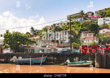 Fort-de-France, Martinique - 3. Januar 2018: Farbenfrohe Häuser klettern auf den Hügel mit Blick auf einen ruhigen Hafen, wo kleine Fischerboote vor Anker liegen. Stockfoto