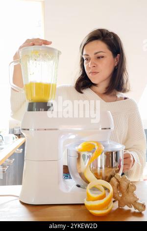 Eine Frau mahlt Orangen und Ingwer in einer Küchenmaschine Stockfoto