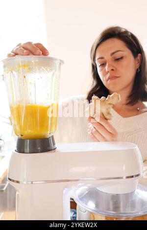 Eine Frau mahlt Orangen und Ingwer in einer Küchenmaschine Stockfoto