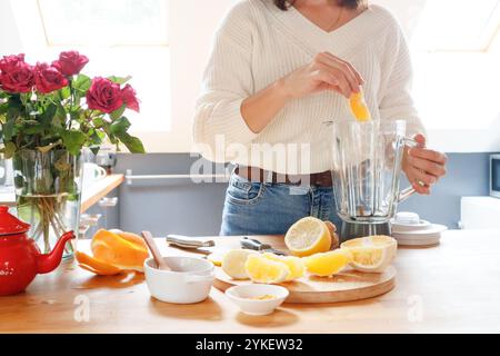 Eine Frau fügt Zitruszutaten für Tee in einen Mixbecher Stockfoto