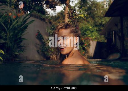 Glückliche Frau, die am sonnigen Tag im Pool schwimmt Stockfoto