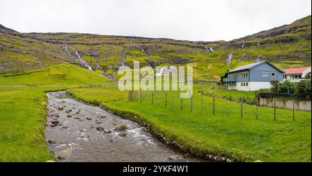 Tjornuvik Stadt mit farbenfrohen Häusern, umgeben von Bergen, Wasserfällen und Flüssen an der Nordküste von Streymoy in Färöer touristische Touren und Entdeckungen Stockfoto