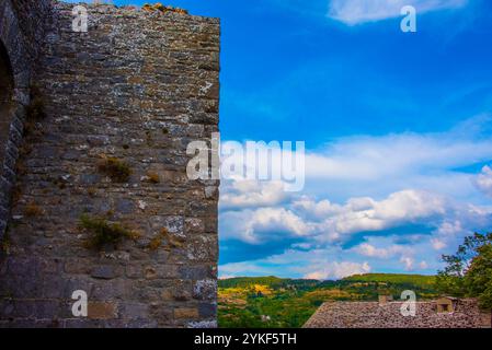 Riesige weiße Wolken mit blauem Sommerhimmel bilden die Kulisse für die alten Mauern einer mittelalterlichen Burg in Chiusi Della Verna, Arezzo, Toskana, Italien Stockfoto