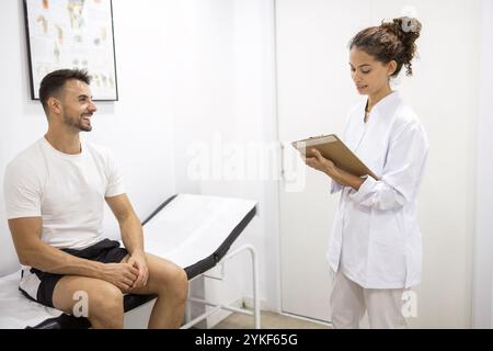 Ein Arzt berät einen lächelnden Patienten in einem orthopädischen Büro der Raum verfügt über medizinische Plakate und eine professionelle Atmosphäre, die die Patie hervorhebt Stockfoto