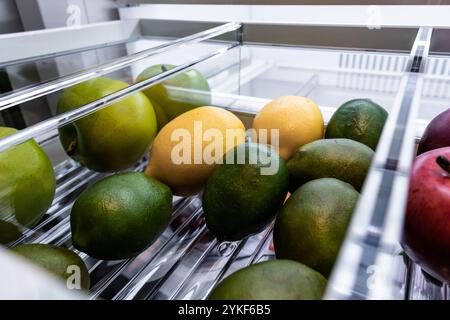 Eine Auswahl an frischem Obst, darunter Limetten, Zitronen und Äpfel, die in einer Kühlschublade angeordnet sind. Stockfoto