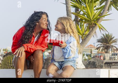 Ein Mädchen und ihre Mutter teilen einen lustigen Moment im Freien das Mädchen scheint das Stuve-Wiedemann-Syndrom zu haben, Narben und Flecken sind an ihren Beinen bemerkt, Stockfoto