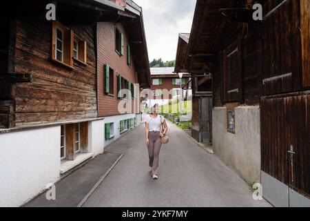 Eine junge asiatin schlendert an traditionellen Holzhäusern im malerischen Dorf Lauterbrunnen in der Schweiz, umgeben von der ruhigen Kulisse von t Stockfoto