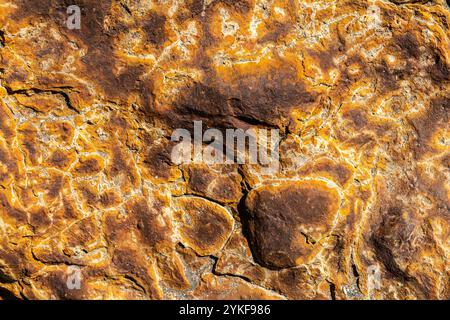 Aus nächster Nähe mit detaillierten Texturen und leuchtenden Orange- und Gelbtönen natürlicher Schwefelgesteine, die durch geologische Prozesse entstanden sind Stockfoto