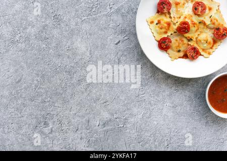 Teller mit Ravioli gefüllt mit Ziegenkäse und süßen karamelisierten Zwiebeln, serviert mit einer reichhaltigen Tomatensauce und garniert mit kandierten Kirschtomaten Stockfoto