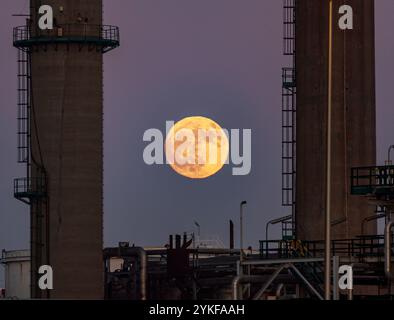 Ein markanter Vollmond erleuchtet den Dämmerhimmel, der sich über den industriellen Silhouetten in Porto, Portugal, erhebt. Stockfoto