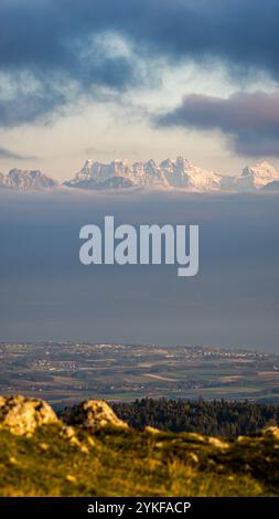 Ein atemberaubender Blick auf die schneebedeckten Gipfel des Schweizer Juras während eines Sonnenuntergangs von Dent de Vaulion aus, der Schichten malerischer Landschaft unter dr. Stockfoto