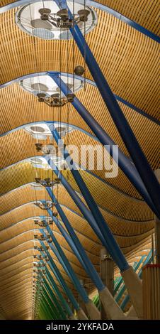 Ein beeindruckender Blick auf die geschwungene, moderne Innenarchitektur des Flughafens Madrid Barajas mit Holzpaneelen und blauen Säulen Stockfoto