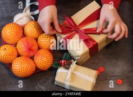 Frau, die eine Kiste einpackt. Nahaufnahme von weiblichen Händen, die ein Band halten. Weihnachtsfeier. Stockfoto
