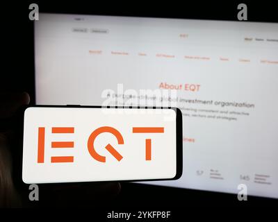 Deutschland. August 2024. In dieser Abbildung hält ein Mann ein Smartphone mit dem Logo der schwedischen Investmentmanagementgesellschaft EQT ab vor der Website. Quelle: SOPA Images Limited/Alamy Live News Stockfoto