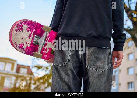 Skateboarder in Baggy-Jeans mit kratzenden Skateboardern auf der City Street. Der Teenager ist Skateboarding. Konzept der Jugendsubkultur Stockfoto