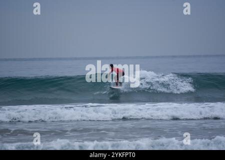 Laredo, Spanien, 18. November 2024: Der Surfer in Rot auf den Wellen, am 18. November 2024 am Strand La Salve in Laredo, Kantabrien, Spanien. Quelle: Javier Linares Misioner / Alamy Live News. Stockfoto