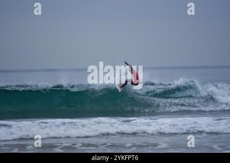 Laredo, Spanien, 18. November 2024: Der Surfer in Rot auf den Wellen, am 18. November 2024 am Strand La Salve in Laredo, Kantabrien, Spanien. Quelle: Javier Linares Misioner / Alamy Live News. Stockfoto