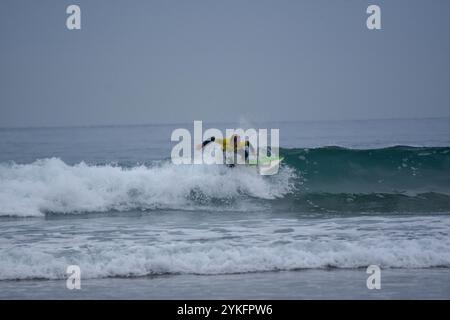 Laredo, Spanien, 18. November 2024: Der Surfer in Gelb auf den Wellen, am 18. November 2024 am Strand La Salve in Laredo, Kantabrien, Spanien. Quelle: Javier Linares Misioner / Alamy Live News. Stockfoto