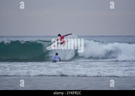 Laredo, Spanien, 18. November 2024: Der Surfer in Rot auf den Wellen, am 18. November 2024 am Strand La Salve in Laredo, Kantabrien, Spanien. Quelle: Javier Linares Misioner / Alamy Live News. Stockfoto