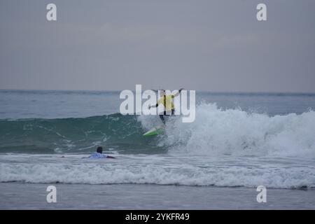 Laredo, Spanien, 18. November 2024: Der Surfer in Gelb auf den Wellen, am 18. November 2024 am Strand La Salve in Laredo, Kantabrien, Spanien. Quelle: Javier Linares Misioner / Alamy Live News. Stockfoto