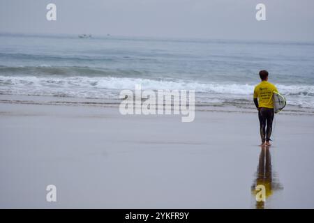 Laredo, Spanien, 18. November 2024: Der gelbe Surfer, der am 18. November 2024 am Strand La Salve in Laredo, Kantabrien, Spanien, ins Wasser einsteigt. Quelle: Javier Linares Misioner / Alamy Live News. Stockfoto