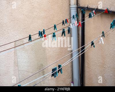 Mehrfarbige Kleiderschalen auf Wäscheleinen ohne Kleidung auf Betonwandhintergrund im Raum des alten Hauses. Stockfoto