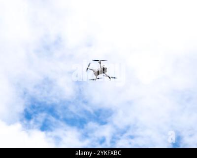 Fliegende Drohne auf blauem Himmel Hintergrund. Moderner weißer UAV-Drohnen-Quadcopter mit Kamera wird gesteuert, um in der Luft zu bleiben. Stockfoto