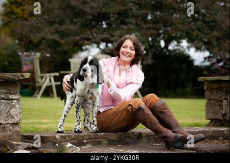 Eine Frau mittleren Alters saß und streichelte ihren älteren Cocker Spaniel Hund. Stockfoto