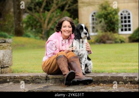 Eine Frau mittleren Alters saß und streichelte ihren älteren Cocker Spaniel Hund. Stockfoto