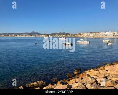 Malerische Aussicht über die Bucht mit Booten vor Anker, man Fishing und Costa Blanca Küste dahinter Stockfoto