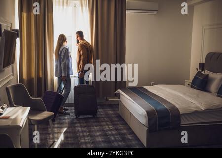 Das junge glückliche Paar ist im Urlaub. Touristen kamen mit ihren Koffern im Hotelzimmer an. Stockfoto