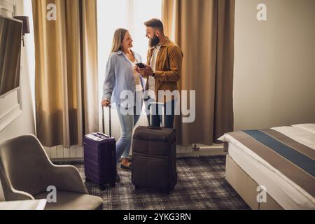 Das junge glückliche Paar ist im Urlaub. Touristen kamen mit ihren Koffern im Hotelzimmer an. Stockfoto