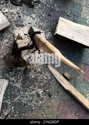 Aus nächster Nähe eine Axt, die in einen Holzstamm eingebettet ist, umgeben von Holzspänen, die traditionelle Holzhackung zeigt. Perfekt für rustikale oder Outdoo-Illustrationen Stockfoto