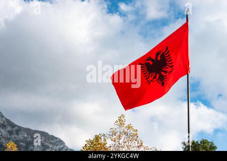 Rote albanische Flagge mit doppelköpfigem schwarzen Adler flattert im Wind auf blauem Himmel Hintergrund, rote und schwarze schöne albanische Flagge auf einem Berg Stockfoto