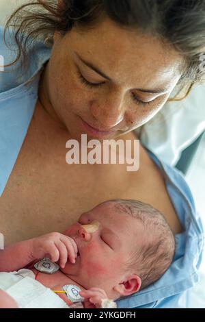 Die neue Mutter hält ihr Neugeborenes in einem Krankenhauszimmer Stockfoto