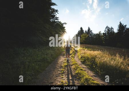 Wanderer mit Rucksack auf einem sonnendurchfluteten Weg in den Beskiden, Tschechien. Erleben Sie Abenteuer und Natur, umgeben von Wäldern und Naturgebieten Stockfoto