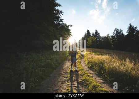 Wanderer mit Rucksack auf einem sonnendurchfluteten Weg in den Beskiden, Tschechien. Erleben Sie Abenteuer und Natur, umgeben von Wäldern und Naturgebieten Stockfoto