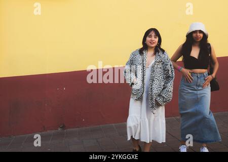 Guanajuato, Mexiko - 4. Februar 2024: Zwei stilvolle junge Frauen vor einer bunten Mauer in Guanajuatos Altstadt. Stockfoto