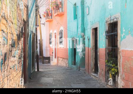 Eine farbenfrohe Gasse in Guanajuato, Mexiko, gesäumt von pastellfarbenen Kolonialgebäuden, schmiedeeisernen Balkonen und einer lebhaften Einrichtung, die das To unterstreicht Stockfoto