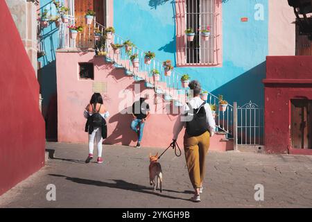 Guanajuato, Mexiko - 4. Februar 2024: Einheimische spazieren entlang einer kopfsteingepflasterten Straße in Guanajuatos Altstadt, vorbei an lebhaften Kolonialgebäuden, Captur Stockfoto