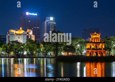 Dies ist ein nächtlicher Blick auf die Skyline in und den berühmten Ngoc Son Tempel am Hoan Kiem See am 15. Juli 2023 in Hanoi, Vietnam Stockfoto