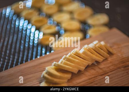 Frische Bananenscheiben liegen auf einem hölzernen Schneidebrett und können als Zutaten verwendet werden. Die Bananenscheiben sind in einer Reihe angeordnet und laden zum Sternen ein Stockfoto