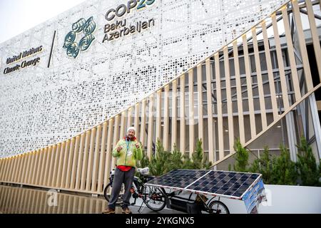 Baku, Aserbaidschan am 18. November 2024. Ein Klimakünstler, der mit seinem Fahrrad die Welt bereist, um das Bewusstsein für die Klimakrise zu schärfen, steht vor dem Haupteingang der UN-Klimakonferenz COP29, einer Veranstaltung des UNFCCC im Olympiastadion von Baku. Die COP29, die vom 11. Bis 22. November läuft, konzentriert sich auf die Klimafinanzierung. Quelle: Dominika Zarzycka/Alamy Live News. Stockfoto